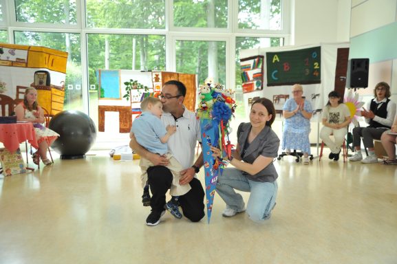 Eine Gruppe von Menschen in einem Raum, darunter ein Erwachsener mit einem Kind und eine Frau.