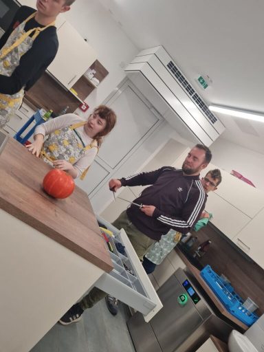 Eine Gruppe von Personen in einer Küche, einige tragen Schürzen und arbeiten zusammen.