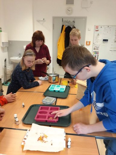 Gruppenschüler arbeiten an einem Tisch mit Farbmischung und Materialien.