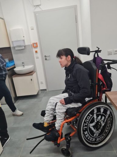 Mädchen im Rollstuhl, sitzt in einer modernen Küche, mit Blick zur Seite.