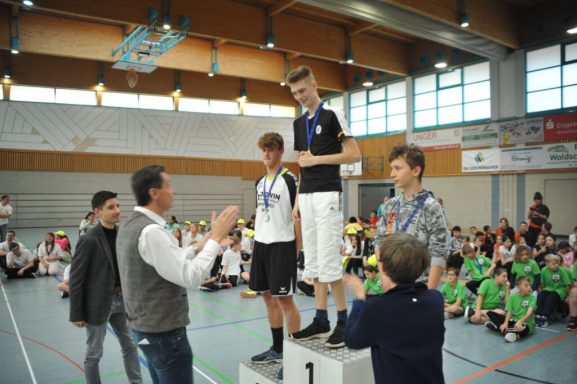 Drei Jungs stehen auf dem Treppchen und erhalten Medaillen bei einem Wettkampf.