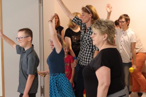 Menschen mit erhobenen Händen, die an einer Aktivität oder Veranstaltung teilnehmen.