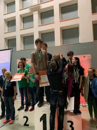 Gruppe von Kindern und Jugendlichen auf dem Siegertreppchen bei einer Preisverleihung.