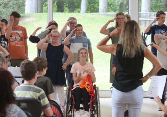 Personen in einer Gruppe stehen aufrecht und salutschieren während einer Veranstaltung.