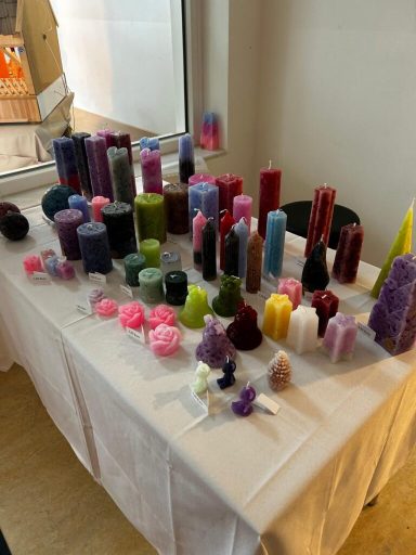 Bunte Kerzen in verschiedenen Formen und Größen auf einem Tisch arrangiert.