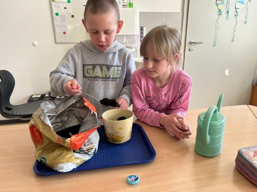 Zwei Kinder beim Zubereiten von etwas mit Chips, einer Schüssel und einer Flasche.