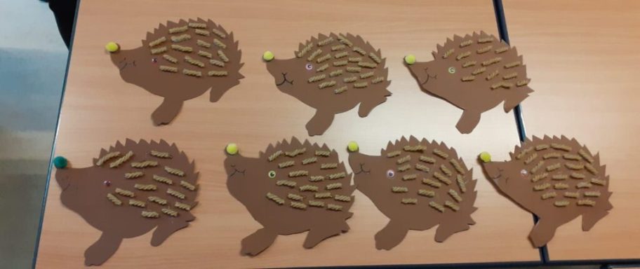 Braune Igelfiguren mit bunten Köpfchen auf einem Tisch angeordnet.