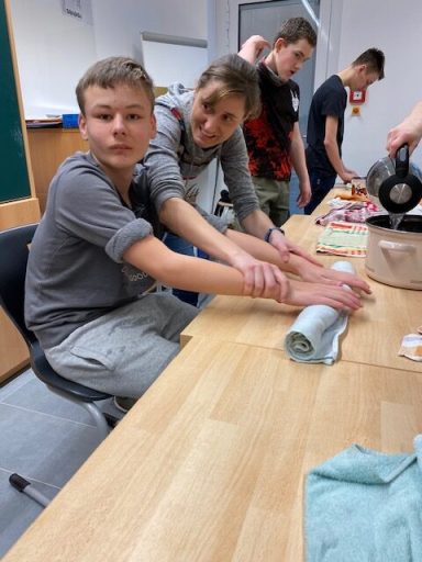 Zwei Jugendliche arbeiten gemeinsam an einem Tisch und bereiten Materialien vor.