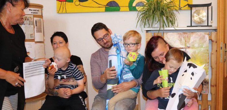 Familie mit zwei Erwachsenen und vier Kindern, die Spielzeug halten und sich unterhalten.