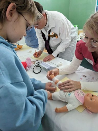 Kind kümmert sich um eine Puppenpuppe, während Erwachsene am Tisch arbeiten.