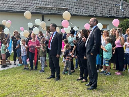 Gruppe von Menschen, darunter Kinder und Erwachsene, mit Ballons im Freien.