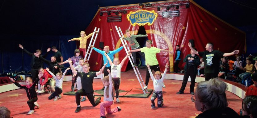 Kinder und Jugendliche führen eine Zirkusaufführung im Zelt auf.