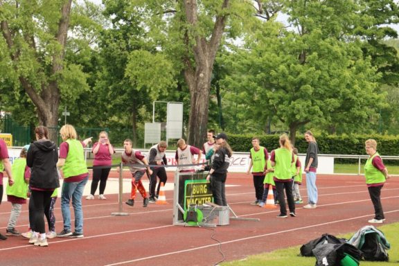 Gruppierung von Menschen in grünen Westen auf einem Sportplatz bei einer Veranstaltung.