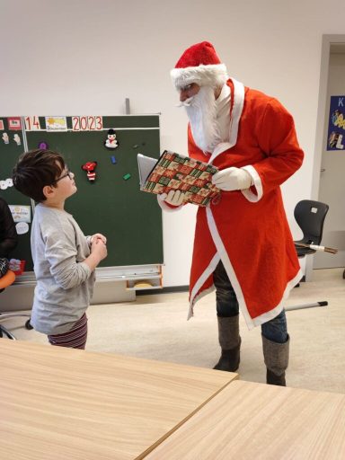 Ein Santa Claus in einem roten Anzug überreicht einem Kind ein Geschenk.