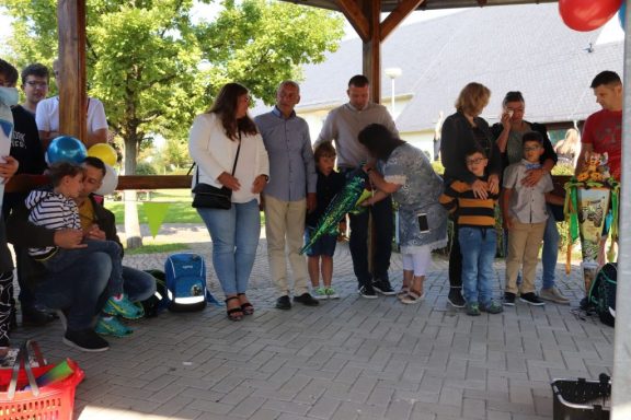 Feierliche Zusammenkunft von Familien und Kindern unter einem Pavillon im Freien.