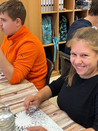 Lächelnde junge Frau bei einer kreativen Aktivität, ein Junge sitzt neben ihr.