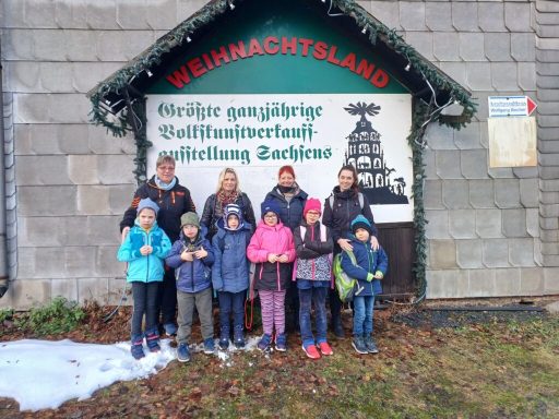 Gruppe von acht Personen vor einem Weihnachtsland-Schild in winterlicher Umgebung.