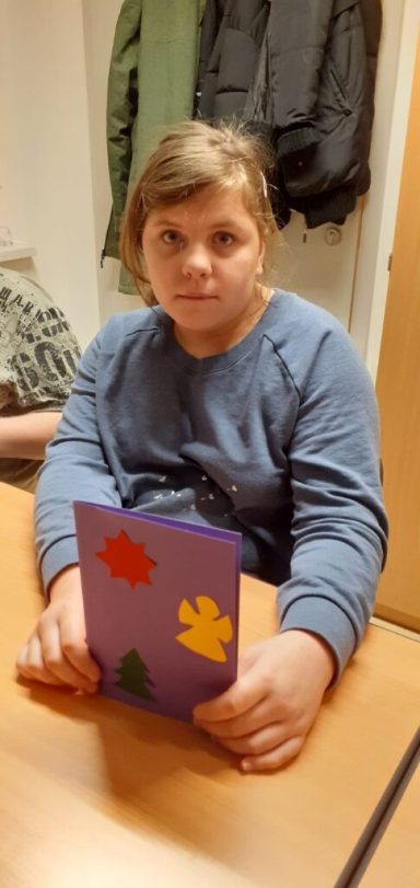 Ein Kind hält ein buntes Bastelbuch mit Laubmotiven in der Hand.