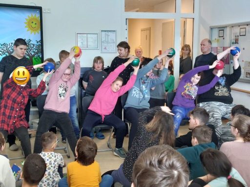 Gruppenevent mit Menschen, die sich mit Bällen dehnen und bewegen, im Klassenraum.