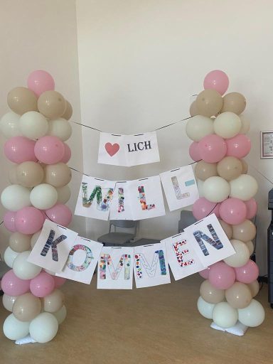 Bogen aus bunten Ballons mit Schildern "WILL KOMMEN" und "❤️ LDR".