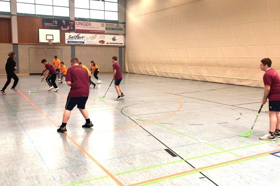 Sportliche Aktivität in einer Halle mit Spielern, die Floorball spielen.
