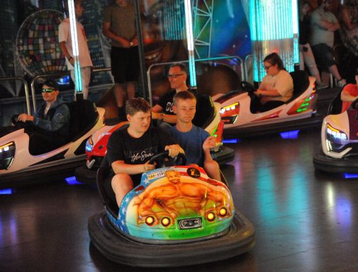 Zwei Jungen fahren zusammen auf einem Bumpercar in einem Vergnügungspark.