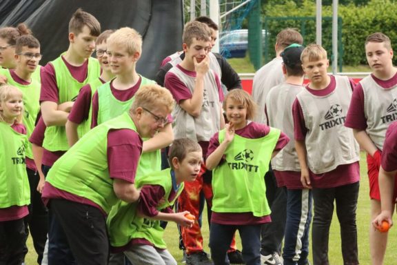 Gruppe von Kindern in grünen Westen, die an einem Outdoor-Spiel teilnehmen.