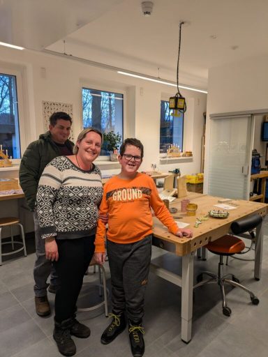 Familie steht in einer modernen Küche, lächelnd und bereit zum Kochen.