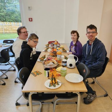 Familie sitzt an einem Tisch mit Essen und Dekoration für eine Feier.