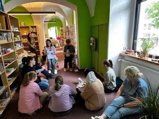 Eine Gruppe von Menschen sitzt in einem Raum und hört einer Person zu, die spricht.