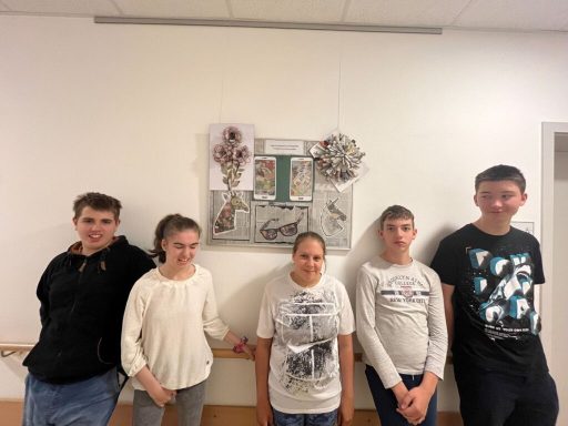 Fünf Jugendliche stehen lächelnd vor einer Kunstinstallation an der Wand.