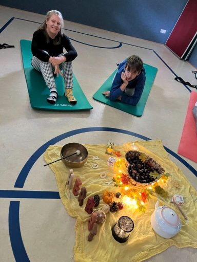 Zwei Personen auf Matten, umgeben von eine Zeremonie mit Speisen und Kerzen.