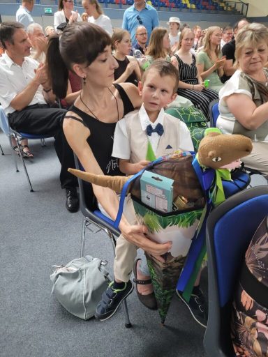 Eine Frau mit einem Jungen auf ihrem Schoß, umgeben von Publikum in einem Saal.