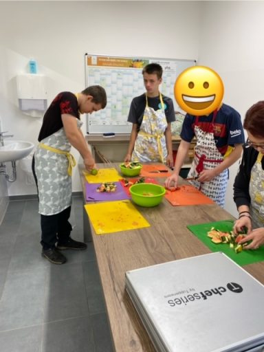 Eine Gruppe von Personen in Schürzen, die Zutaten in einer Küche vorbereiten.