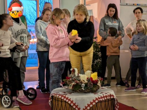 Eine Gruppe von Kindern und Erwachsenen versammelt sich um eine weihnachtliche Dekoration.