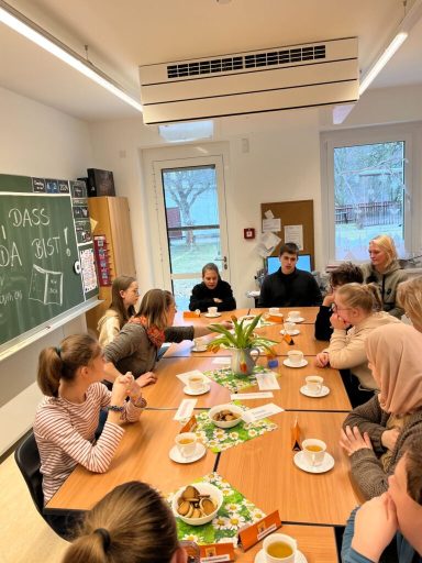 Gruppe von Personen an einem Tisch bei einer Besprechung mit Snacks und Getränken.