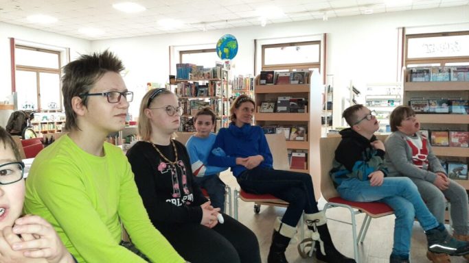 Gruppe von Jugendlichen, die aufmerksam in einer Bibliothek sitzen.