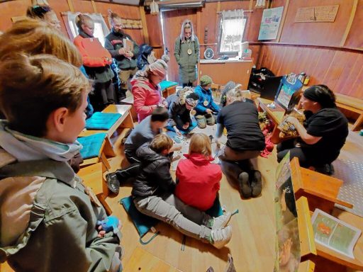 Gruppensitzung von Kindern und Erwachsenen in einem Raum, einige spielen auf dem Boden.