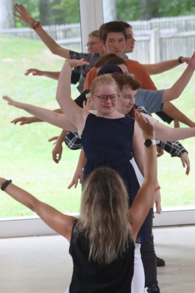 Gruppenaktivität mit mehreren Personen, die synchron die Arme ausstrecken.