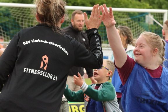 Kinder und Erwachsene feiern gemeinsam beim Sport, lächelnd und mit hohen Fünf.