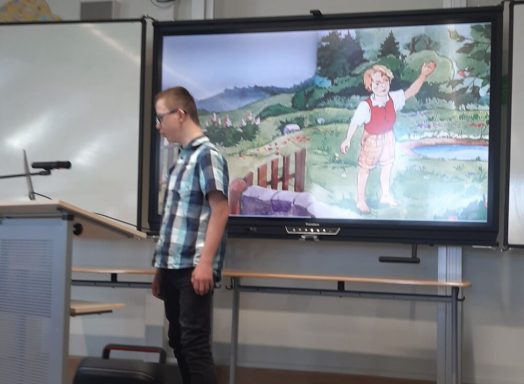 Junger Mann steht vor einer Präsentation mit einer bunten Landschaft und einem Kind.