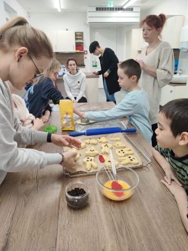 Kinder und Erwachsene backen zusammen, Teig wird in eine Form gefüllt.