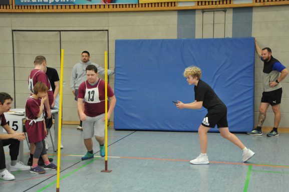 Jugendliche beim Wettkampf in einer Sporthalle, Training mit Hindernissen und Zeitmessung.