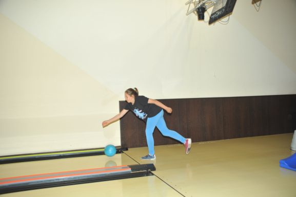 Ein Kind wirft eine Bowlingkugel in einer Bowlingbahn.