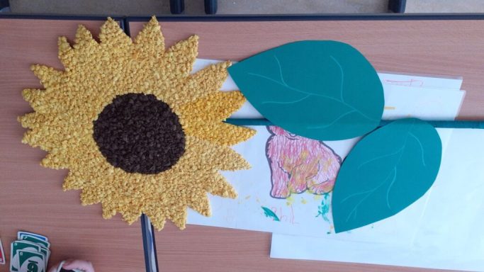 Ein großer, gelber Sonnenblume mit zwei grünen Blättern auf einem Tisch.