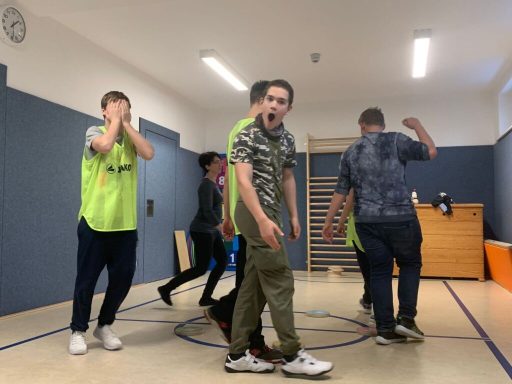 Jugendliche in Sportkleidung spielen in einer Turnhalle und zeigen unterschiedliche Emotionen.