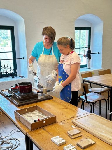 Zwei Personen arbeiten gemeinsam an einem Tisch, dabei bereiten sie eine Mischung vor.