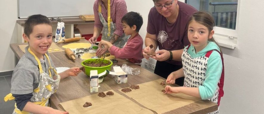 Kinder und Erwachsene bereiten gemeinsam Essen in einer Küche vor.