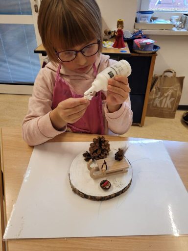 Ein Kind dekoriert einen Kuchen mit einer weißen Spritztüte und verschiedenen Zutaten.