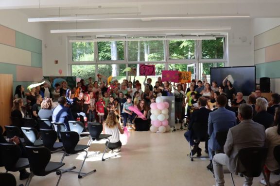 Gruppenevent in einem Raum mit Menschen, bunten Schildern und festlichem Ambiente.